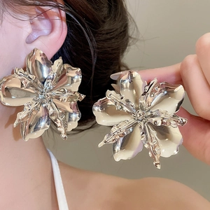 Primo piano di una modella con grandi orecchini a fiore in metallo argento lucido