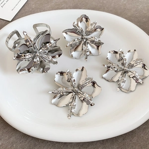 Dettaglio di un set di gioielli a forma di fiore in metallo argento con anelli e orecchini