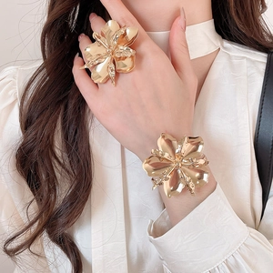 Dettaglio di set anello e bracciale a forma di fiore in metallo dorato su modella
