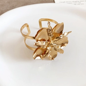 Vista dettagliata del fiore in metallo dorato lucido su questo elegante bracciale a fascia.