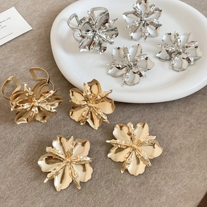 Dettaglio di un set di gioielli a forma di fiore in metallo oro e argento su un piatto.