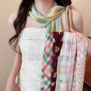 Close-up of various vintage floral and striped silk scarf necklaces for women.