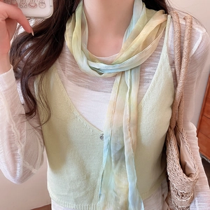 Close-up of French retro gradient silk scarf necklace on model with light green vest.