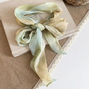 Close-up of French vintage silk scarf necklace with green tie-dye fabric bow