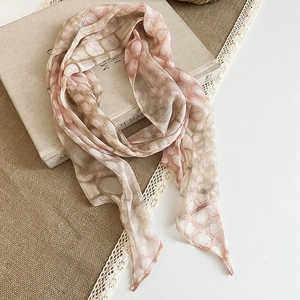 Close-up of a French vintage floral silk scarf with pink abstract print patterns on an old book.