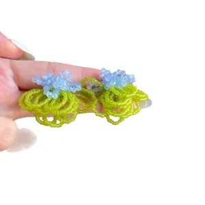 Exquisite handmade floral beaded earrings with light blue crystals and green loop tassels.