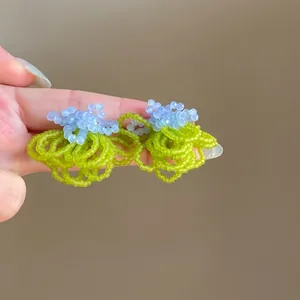 Close-up view of elegant handmade green and blue beaded flower cluster stud earrings.