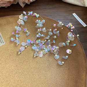 Detailed macro view of iridescent sequin and bead tassel earrings on ceramic plate