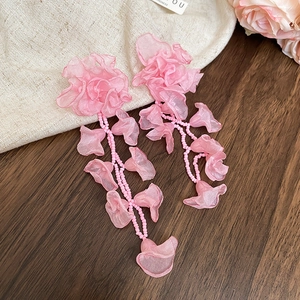 Close-up detail of romantic pink chiffon flower earrings with delicate bead tassels.