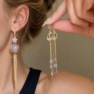 Elegant 18k gold plated long tassel earrings with purple rhinestone flower detail.