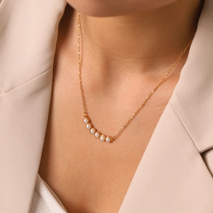 Elegante collar de perlas en el cuello de una mujer, detalle de joyería en acero dorado
