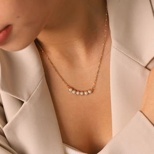 Vista detallada de un elegante collar de acero de titanio dorado con seis perlas