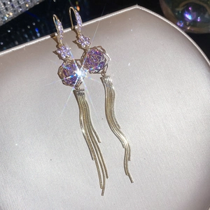 Close-up of elegant purple rose earrings with sparkling crystals and long gold tassels