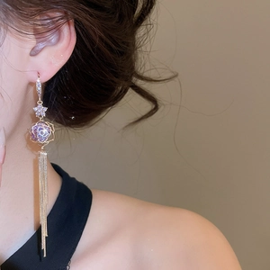 Detail shot of elegant 18k gold plated tassel earrings with purple flower crystal