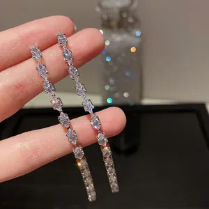 Dettaglio di lunghi orecchini scintillanti con pietre di zircone cubico taglio marquise.