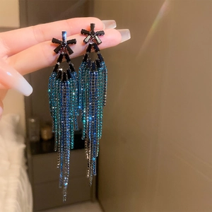 Dettaglio macro di orecchini a frange con strass blu e verde acqua lunghi e scintillanti