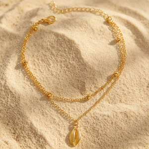 Detailansicht eines böhmischen zweilagigen Goldfußkettchens mit Muschel anhänger am Strand