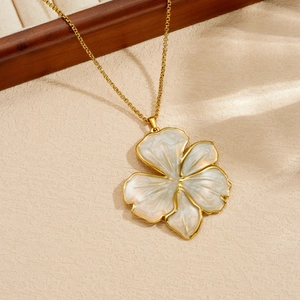 Primo piano di una collana in acciaio dorato con dettagli del ciondolo a fiore perlato