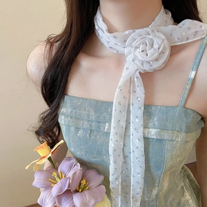 Gros plan d'un collier écharpe en mousseline florale blanche avec une grande fleur de rose