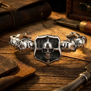 Detailed close-up of a vintage punk skull and shield cuff bracelet for men in silver.