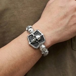 Detailed macro view of punk style silver titanium steel bracelet featuring skull and cross