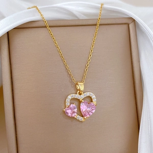 Exquisites Detail eines rosa herzförmigen Zirkonia-Anhängers an einer goldenen Titanstahlkette