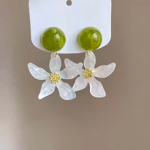 Detailed macro view of forest style green and white resin floral drop pendant earrings.