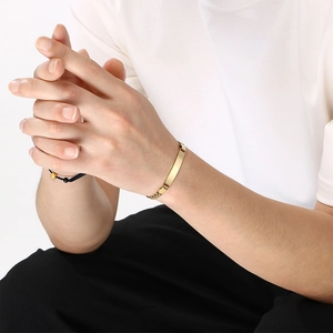 Gedetailleerde weergave van een minimalistische gouden ID-armband met Figaro-ketting