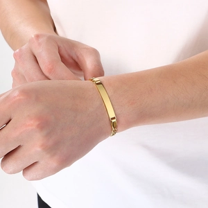 Detailopname van een graveerbare gouden ID-plaat op een Cubaanse schakelarmband.