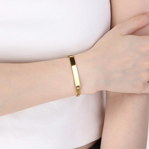 Detailopname van een minimalistische vergulde Figaro-armband met een graveerbare bar op pols