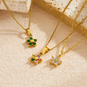 Close-up of three dainty gold-plated flower necklaces with colorful gemstone pendants.