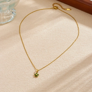 Close-up of gold-plated necklace featuring a delicate green crystal flower pendant