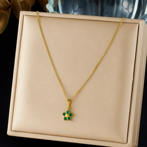 Macro view of an elegant gold-plated necklace with a green crystal flower pendant