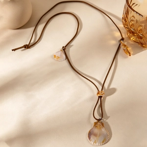 Détail du collier bohème avec pendentif coquillage, cordon tressé et perles ambrées