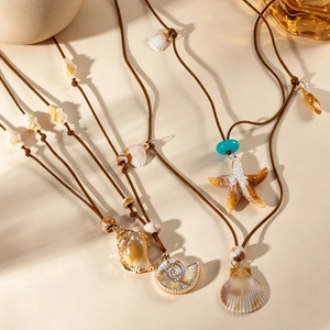 Collier bohème avec pendentif étoile de mer et perles turquoise sur un fond de sable
