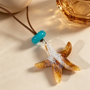 Détail du pendentif étoile de mer vintage avec glaçure ambre et perle bleue sur cordon
