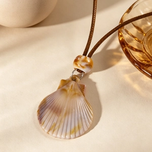 Gros plan d'un pendentif en coquille de pétoncle bohème avec perle ambrée sur cordon