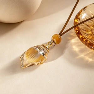 Détail du collier bohème avec pendentif en coquillage et bordure dorée sur fond beige