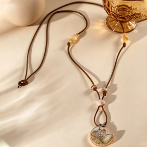 Vue détaillée du pendentif nautile bohème avec bordure dorée sur un collier en cordon ciré
