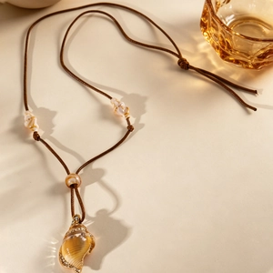 Détail macro du pendentif coquillage bohème avec base dorée et cristaux fins