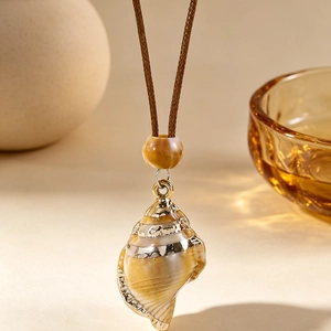 Gros plan d'un pendentif en coquillage naturel avec bords dorés sur un collier tressé