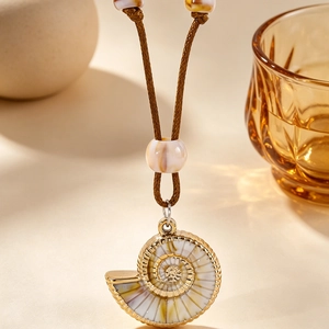 Vue macro d'un pendentif nautile doré sur un collier en cordon tressé marron