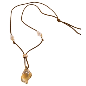 Détail du pendentif coquillage doré bohème sur cordon marron avec petits coquillages