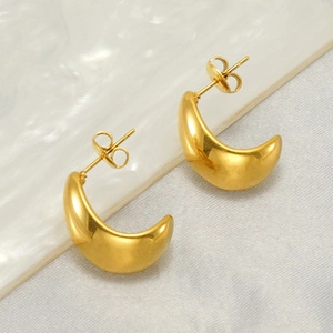 Detail of polished gold crescent earrings with butterfly backings on textured backdrop