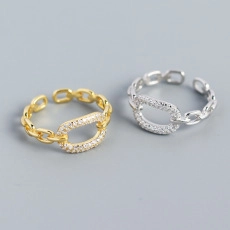 Detailed view of adjustable chain-link rings with oval zircon inlay in gold and silver