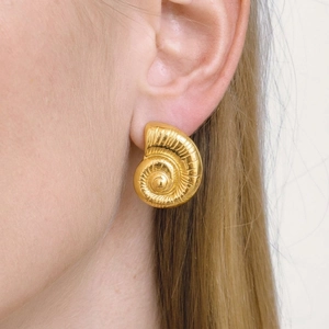 Golden spiral conch stud earrings featuring detailed radial texture on a female model
