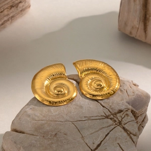 Macro detail of golden nautilus spiral earrings with fine texture on natural stone