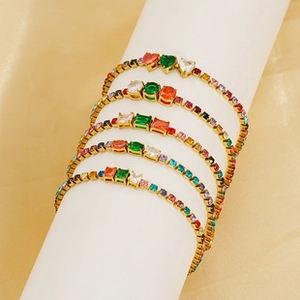 Macro detail of four gold plated bracelets with colorful heart and square zircons