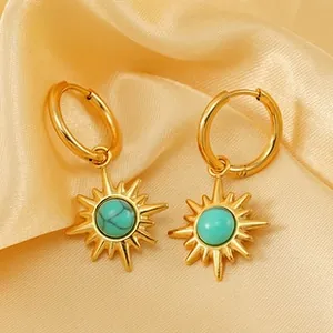 Macro view of gold sun earrings with turquoise stone on soft silk fabric background