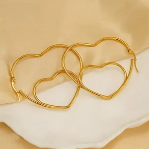 Close-up of gold double heart hoop earrings on elegant silk and ceramic display